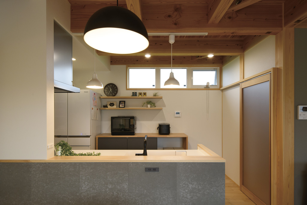 キッチンの腰壁には無機質な質感のSOLIDOをチョイス。照明や水栓、家電の黒色と共にナチュラルな空間のスパイスに